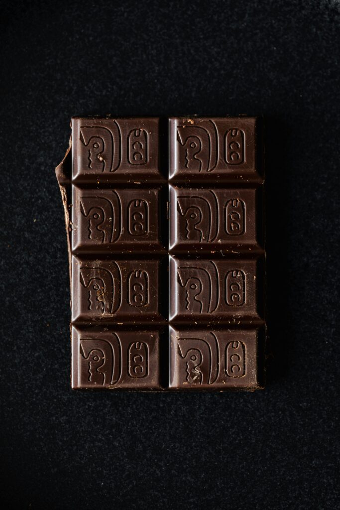 A high-quality close-up of a dark chocolate bar with intricate patterns on a black background.